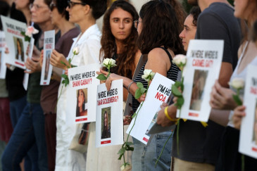 Des personnes portent des photos de personnes disparues lors d'une manifestation pour la libération des otages capturés par le Hamas début octobre.