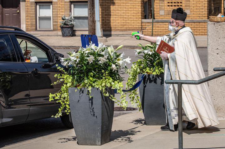 Un prêtre de l'Église Saint-Ambroise qui utilise un pistolet pour ses bénédictions