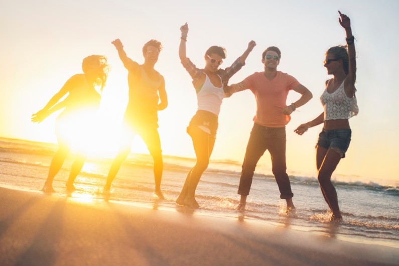 Un coucher de soleil avec des jeunes sur une plage (illustration)