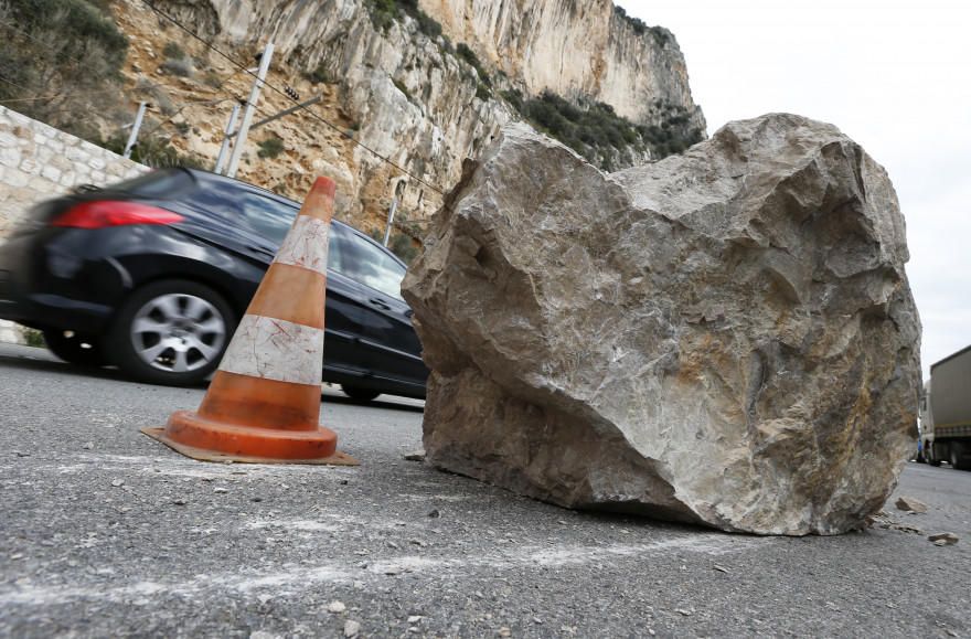 Une voiture passe derriere un roché tombé suite à un éboulement arrachant des caténaires, à Beaulieu-Sur-Mer le 10 février 2013.