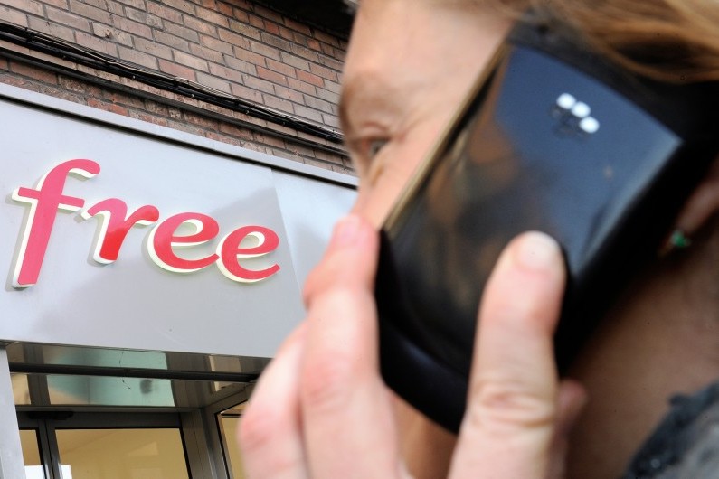 Un homme au téléphone devant une enseigne Free (Illustration)