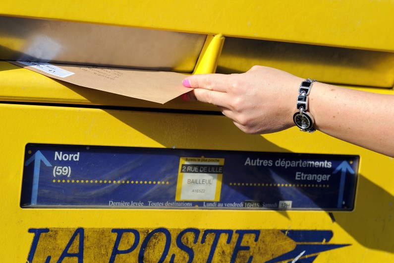 Une habitante de Lille dépose un courrier dans une boîte aux lettres de La Poste, le 10 septembre 2013 (archives)
