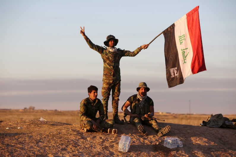 Des soldats irakiens font le signe de la victoire lors d'une opération pour chasser l'EI de Tikrit.