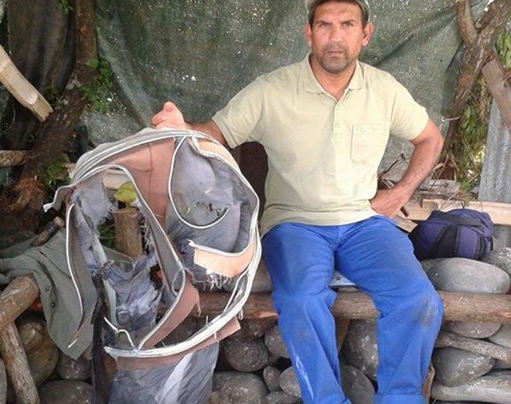 Johnny Bègue, qui a découvert le débris à La Réunion, pose avec le morceau de valise lui aussi trouvé par son association qui nettoyait le littoral.