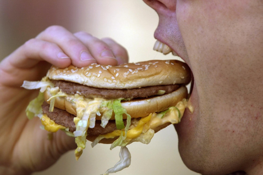 Un homme mange un hamburger dans une rue de Caen, le 10 mars 2011