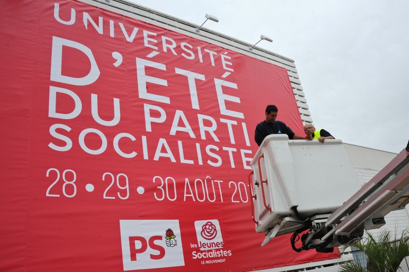 Des ouvriers installent la bannière de l'Université d'été du Parti socialiste à La Rochelle.