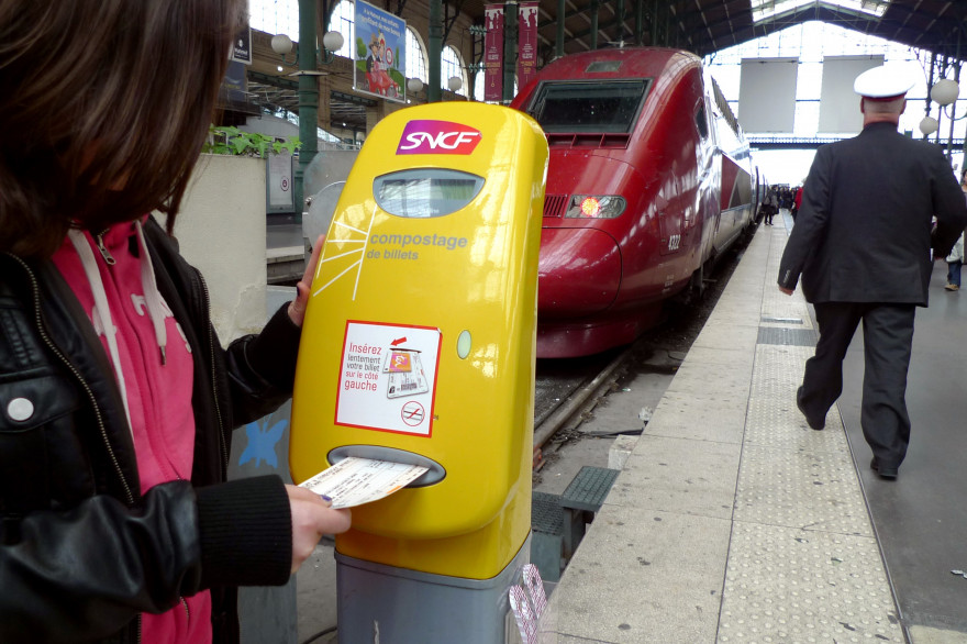 Une utilisatrice composte son billet SNCF dans une gare (illustration)