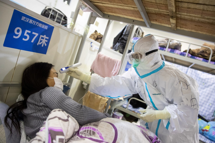 Une membre de l'équipe médicale d'un hôpital de Wuhan prend la température d'une patiente.