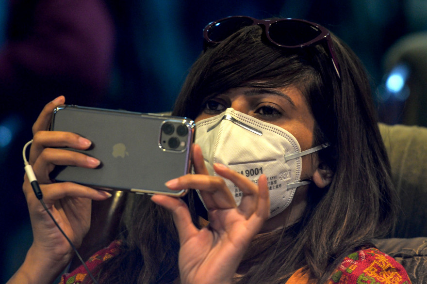 Une journaliste pakistanaise le visage recouvert d'un masque de protection sur son smartphone le 10 mars 2020