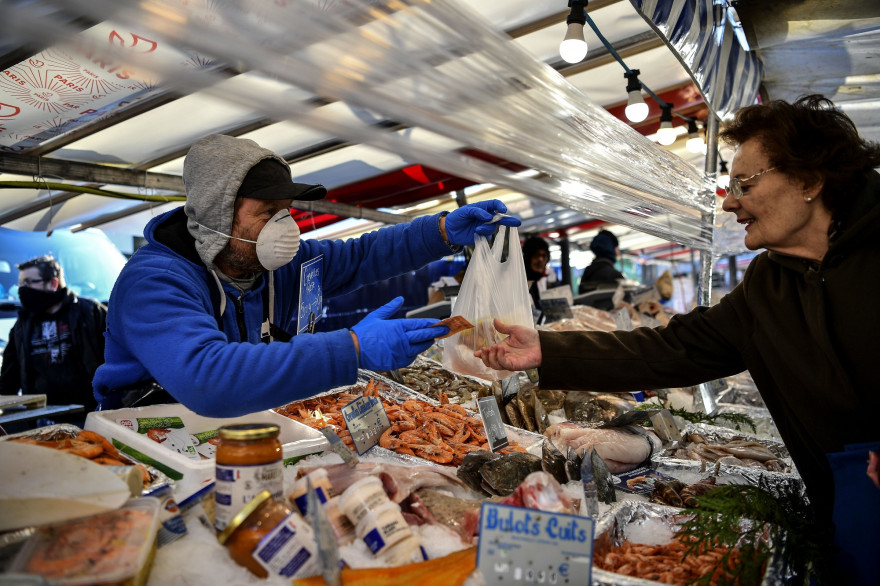 Un poissonier et une cliente sur un marché à Paris le 19 mars 2020.