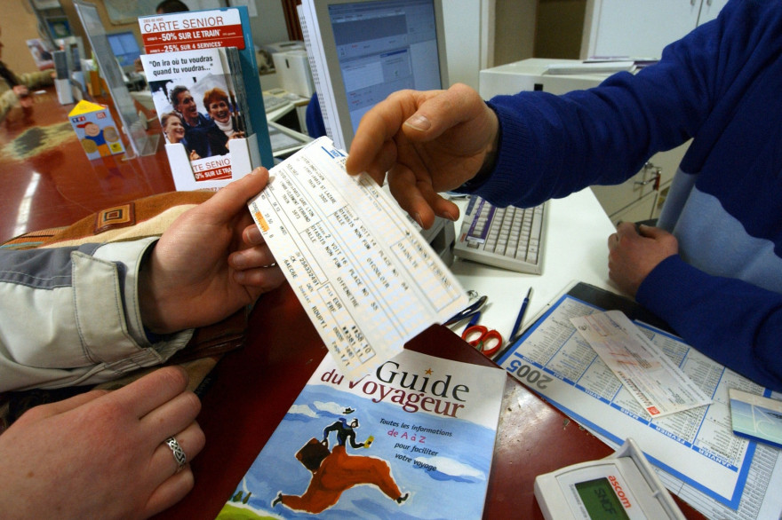 Un homme paye un billet de train dans une gare (illustration)