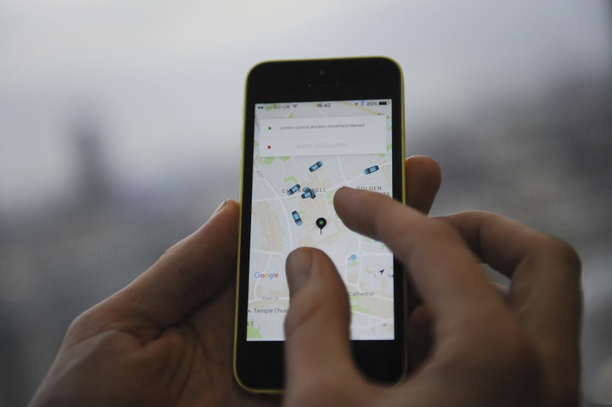 Un homme utilise l'application Uber sur son smartphone (illustration)