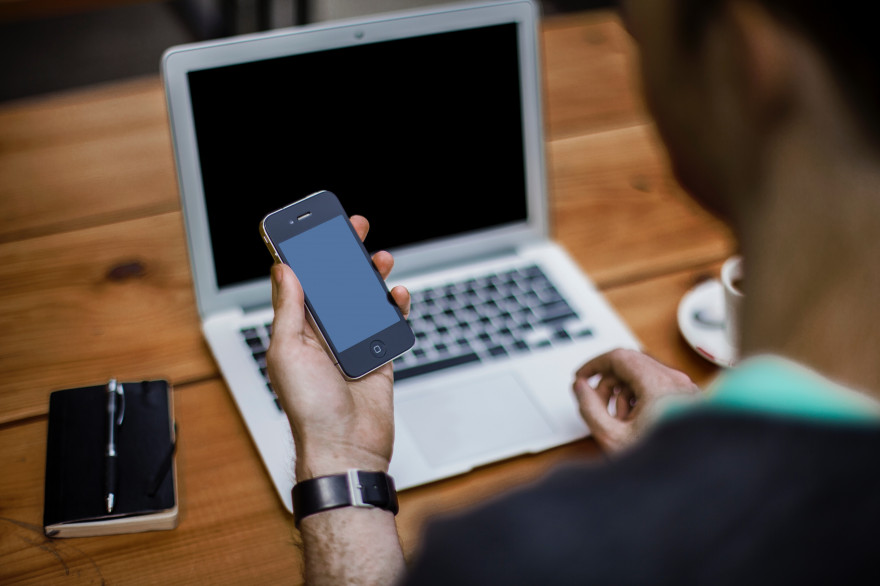 Un homme avec un smartphone et un ordinateur portable (illustration)