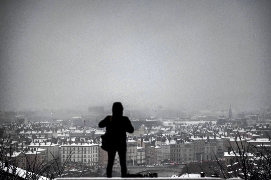 Un homme observant la ville de Lyon sous la neige