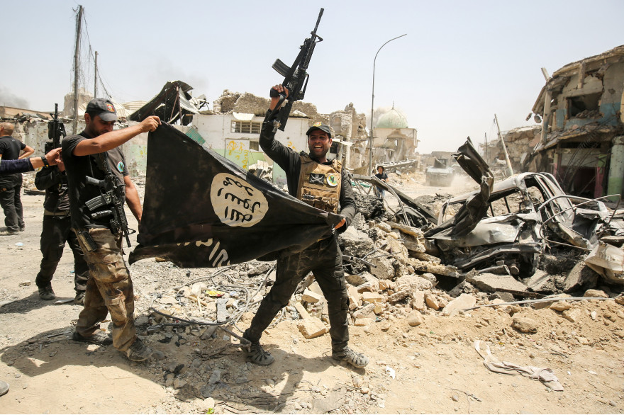 Des forces de l'antiterrorisme irakiennes brandissent un drapeau de Daesh à l'envers dans la vieille ville de Mossoul, le 2 juillet 2017