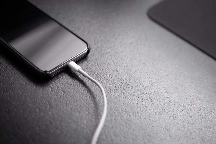 Un téléphone branché à son chargeur (Illustration).