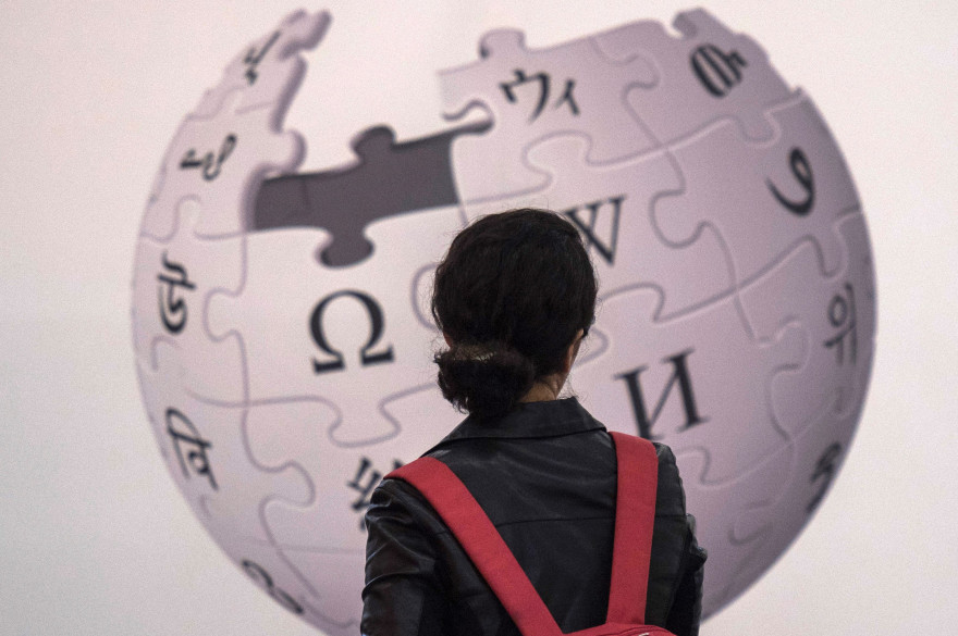 Une femme devant le logo de Wikipedia
