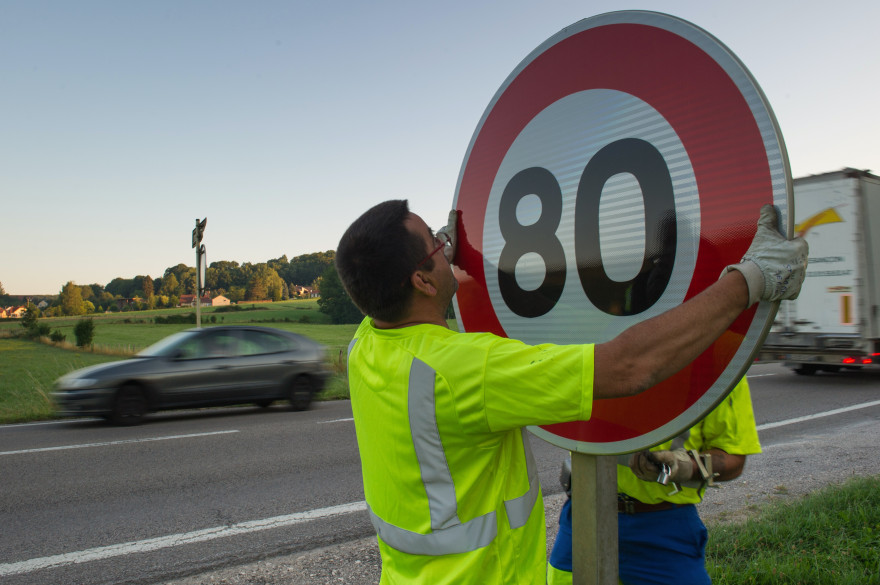 Un employé de la DIR Est installe un nouveau panneau de signalisation sur la nationale 57.