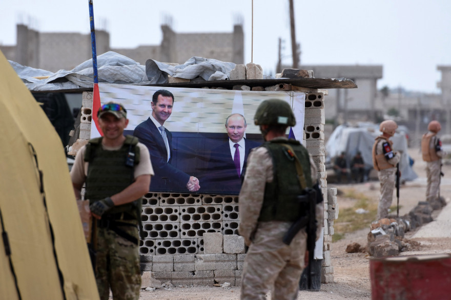 Des militaires russes devant une photo officielle des dirigeants syrien et russe, Bachar al-Assad et Vladimir Poutine