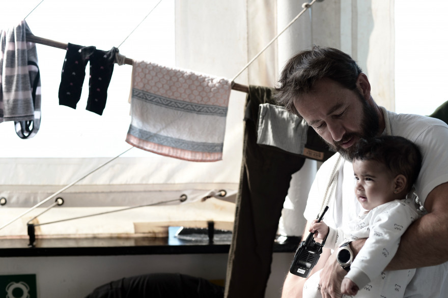 Un homme tient un bébé dans ses bras sur l'Aquarius, mi-juin 2018