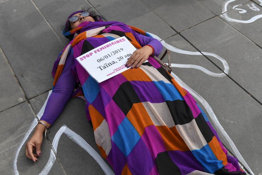 Une femme s'allonge sur le sol de la Place de la République en tenant une affiche intitulée "Stop féminicides"
