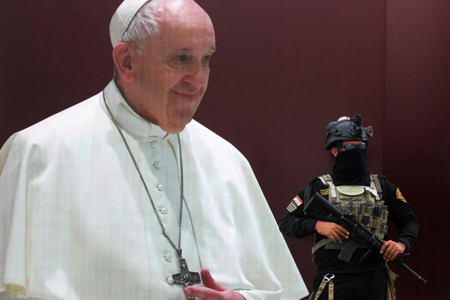 Un militaire irakien à Bagdad devant une affiche annonçant la venue du pape François en Irak