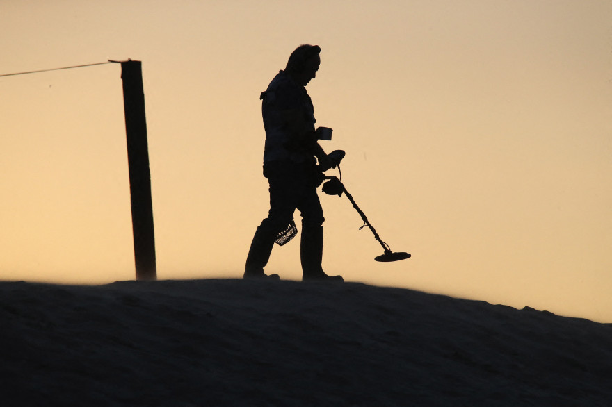 Un homme cherchant des trésors sur la plage avec un détecteur de métaux