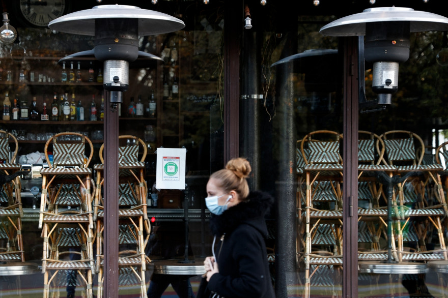 Une femme portant un masque, devant un restaurant fermé pendant le confinement.