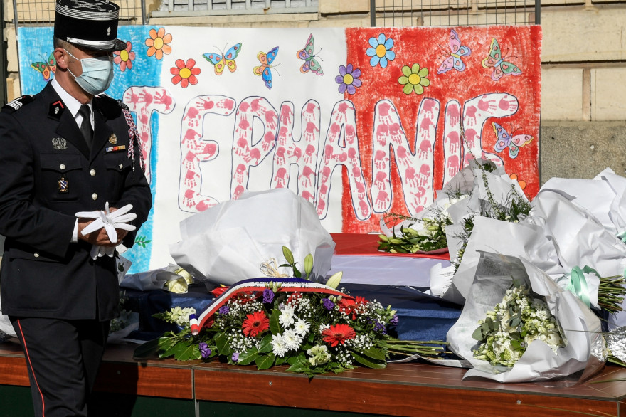 Un policier rend hommage devant des fleurs déposées en hommage à Stéphanie Monferme, une policière locale tuée, lors d’un rassemblement commémoratif le 26 avril 2021 à la mairie de Rambouillet.